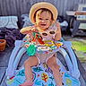 baby, walker, hat, sunglasses, toy, smile, happy, outdoor, child, sunlight, fence, floor, foot, clothing, person, seat, colorful, play, summer, garden