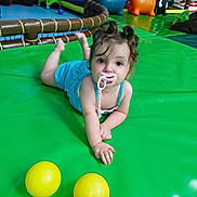 Léanna participe au concours pour gagner de l'argent avec cette photo : baby, blue_dress, child, colorful, curly_hair, cute, face, floor, fun, green_mat, hands, indoor, inflatable_animals, looking_at_camera, pacifier, play_area, playground, toddler, toys, yellow_balls