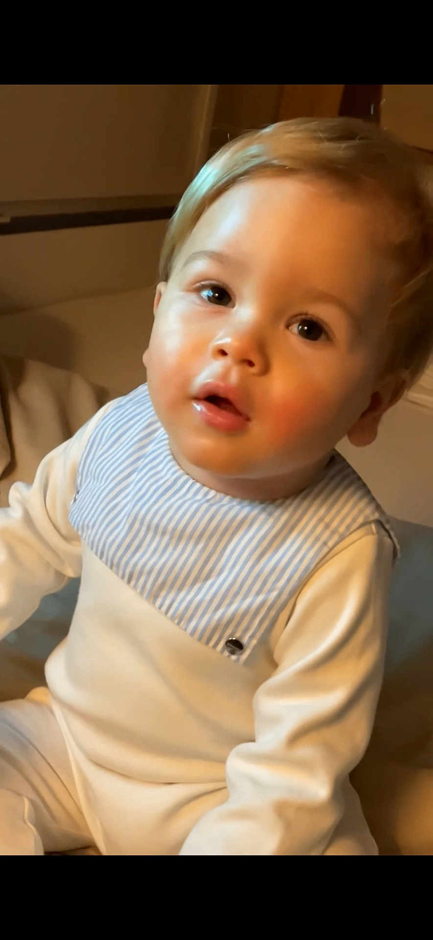 Even a rejoint le concours — aidez-le/la à gagner de superbes lots ! toddler, child, face, portrait, indoor, clothing, bib, white_outfit, curious_expression, seated, young_child, baby, light_skin, blond_hair, warm_lighting, person, cute, closeup, infant, soft_texture