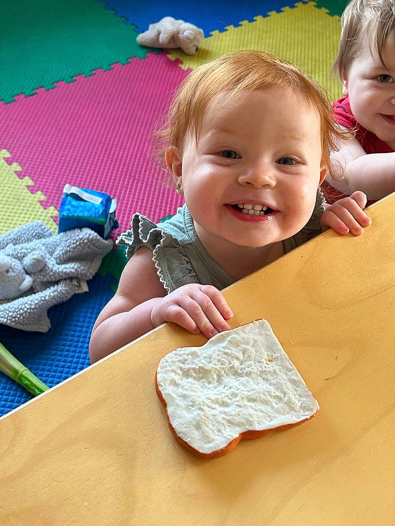 Carleigh is registered to the contest to win money with this photo: baby, baby_products, baby_toddler_clothing, child, dress, eye, finger, fun, happy, joy, leisure, linens, magenta, pattern, person, pink, play, sitting, skin, smile