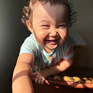 Sutton joined the competition — help win amazing prizes! arm, baby, cheerful, child, close_up, curly_hair, cute, expression, face, happy, indoor, person, portrait, reaching_out, shadow, short_sleeve_shirt, smiling, sunlight, toddler, warm_light