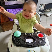 Dusser Dohan participe au concours pour gagner de l'argent avec cette photo : baby, walker, green_shirt, drool, happy, child, indoor, toy, floor, furniture, electronics, purple_cushion, smiling, person, head, arms, eyes, mouth, seat, home
