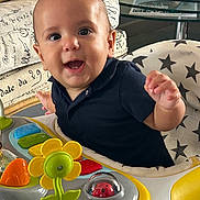 Floriano a rejoint le concours — aidez-le/la à gagner de superbes lots ! baby, child, smiling, toy, activity_center, yellow_flower, ladybug_toy, cushion, star_pattern, indoor, furniture, table, glass, person, happy, cute, infant, playful, black_shirt, closeup