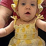 baby, infant, child, portrait, close_up, smiling, wide_eyes, yellow_outfit, bonnet, dress, floral_pattern, sitting, indoor, adult, tattoo, arm, fashion, adorable, camera, family