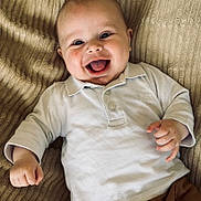 Léio participe au concours pour gagner de l'argent avec cette photo : baby, blanket, brown_pants, casual, child, clothing, cute, face, hand, happy, indoors, infant, lying_down, person, portrait, skin, smiling, texture, white_shirt, young