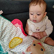 Aëlia participe au concours pour gagner de l'argent avec cette photo : baby, child, clothing, couch, curious, cute, expression, fabric, face, giraffe, hands, illustration, indoor, infant, onesie, pattern, play_mat, seated, spot_pattern, toy