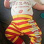 Luke joined the competition — help win amazing prizes! baby, infant, child, clothing, pants, shirt, socks, face, person, laying_down, curious, comfortable, indoor, soft_lighting, striped_pants, text_on_clothing, red, yellow, white, cozy