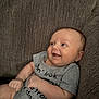 baby, infant, smile, couch, gray_onesie, happy, face, arm, hand, skin, textile, home, relaxation, seated, cute, child, indoors, portrait, person, cozy
