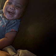 Kurrency is registered to the contest to win money with this photo: baby, bed, blanket, child, closeup, cushion, cute, expression, face, happy, indoors, infant, person, pillow, portrait, resting, skin, sleepwear, smiling, young