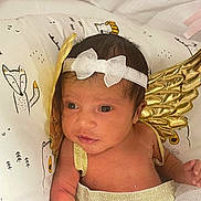 Bailey is registered to the contest to win money with this photo: baby, infant, angel_wings, headband, white_bow, golden_wings, cute, newborn, pillow, fox_pattern, clothing, tutu_skirt, portrait, child, face, looking, indoors, soft_lighting, skin, expression