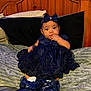 Bella is registered to the contest to win money with this photo: baby, bed, blanket, blue_dress, bow, child, clothing, cute, expression, furniture, headband, indoor, infant, person, pillow, portrait, shoes, sitting, socks, wooden_headboard