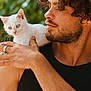 Minotaure a rejoint le concours — aidez-le/la à gagner de superbes lots ! man, kitten, white_cat, curly_hair, beard, outdoor, green_background, shoulder, blue_eyes, affection, portrait, holding, casual_clothing, ring, earring, closeup, pet, animal, friendship, sunlight