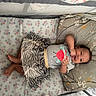 baby, crib, pillow, sheet, smile, child, infant, clothing, pattern, zebra_stripe, floral, cute, happy, lying_down, indoor, playful, person, small_child, toddler, resting