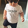 Noah is registered to the contest to win money with this photo: baby, child, toddler, sunglasses, portrait, standing, walking, fashion, clothing, t_shirt, shorts, sneakers, shoes, indoors, floor, tile, blurred_background, front_view, designer_logo, cute