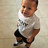 child, toddler, baby, portrait, sunglasses, smiling, face, standing, indoors, tiled_floor, white_shirt, graphic_shirt, black_shorts, sneakers, fashion, cute, looking_at_camera, candid, full_body, photography