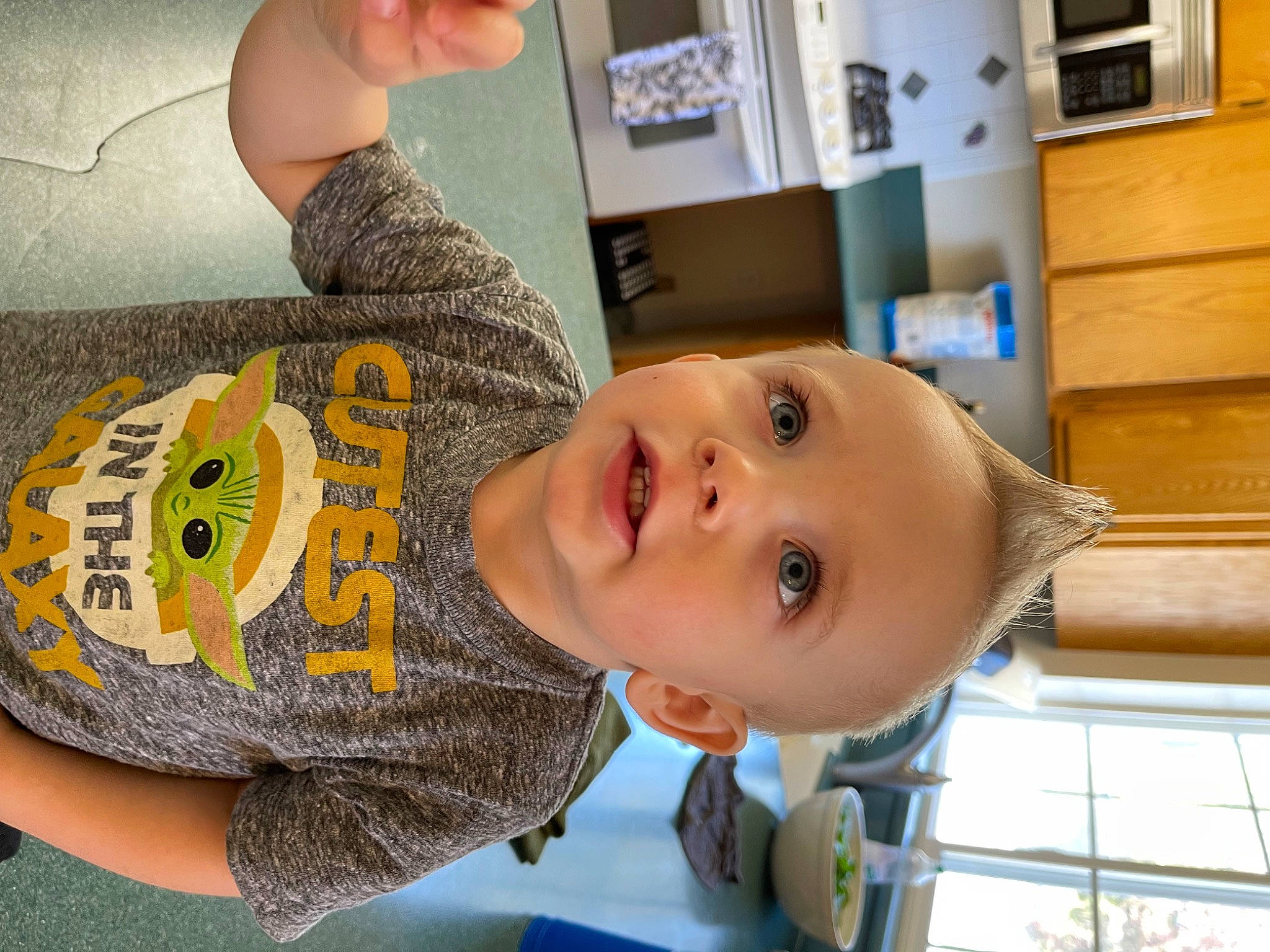 Bentley is registered to the contest to win money with this photo: arm, baby, baby_toddler_clothing, cheek, child, eyelash, facial_expression, finger, gesture, happy, mouth, nose, person, room, shelf, shelving, skin, sleeve, t_shirt, toddler