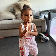 Amélia participe au concours pour gagner de l'argent avec cette photo : toddler, child, smiling, clapping, overalls, minnie_mouse, pink, sandals, indoors, living_room, sofa, shoes, hair_bun, cute, happy, person, floor, playpen, earrings, portrait