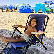 Ruthwika joined the competition — help win amazing prizes! child, beach, sand, smile, chair, umbrella, sunny, vacation, relaxing, shorts, happy, outdoor, sea, summer, holiday, people, blue, sunlight, casual, fun