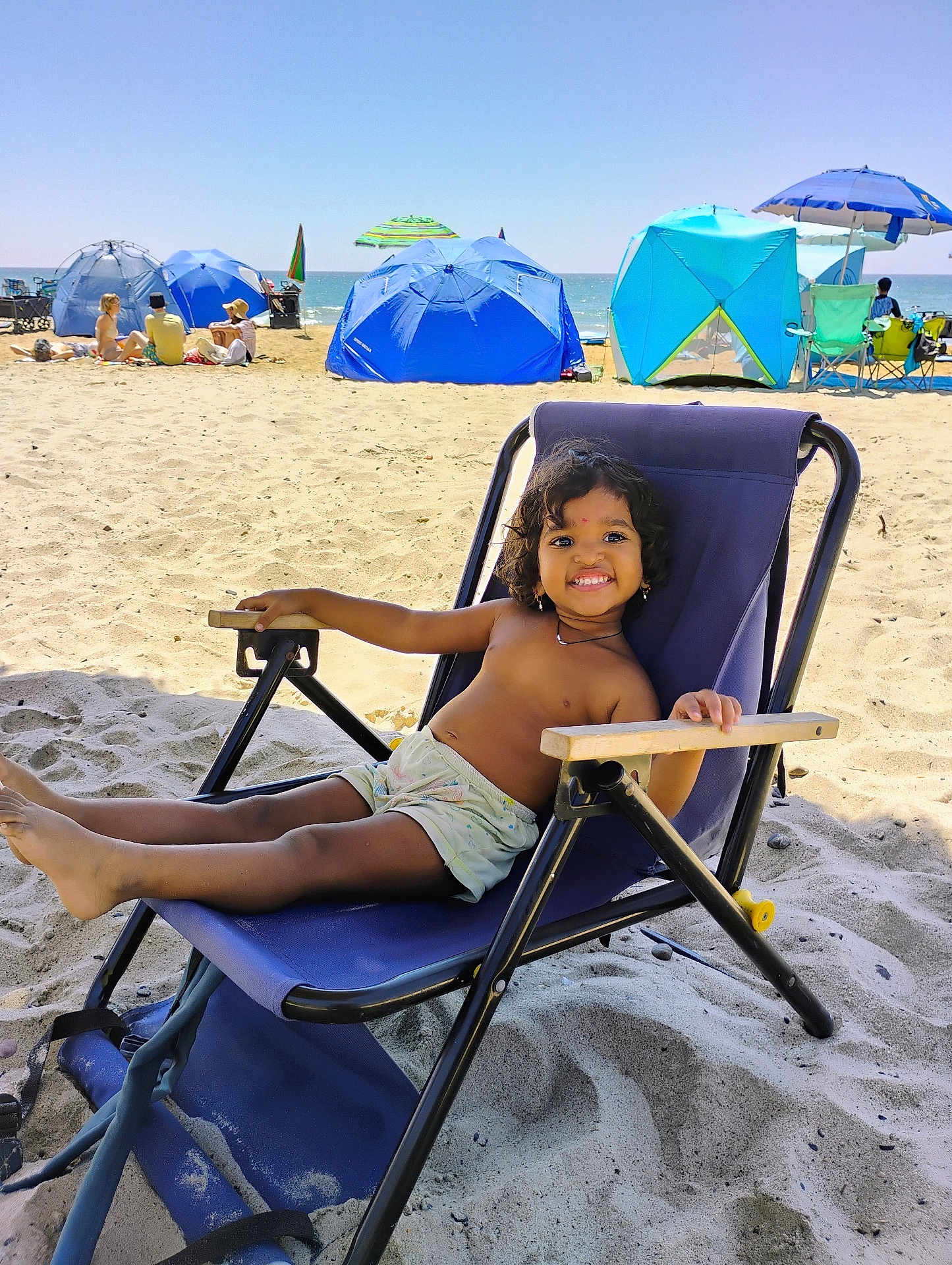 Ruthwika joined the competition — help win amazing prizes! child, beach, sand, smile, chair, umbrella, sunny, vacation, relaxing, shorts, happy, outdoor, sea, summer, holiday, people, blue, sunlight, casual, fun