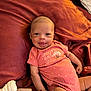 baby, infant, smiling, onesie, pink_clothing, blanket, fabric, cute, child, portrait, face, lying_down, small_hands, happy, young_child, indoors, cozy, soft_lighting, newborn, resting