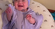 Elleauna is registered to the contest to win money with this photo: baby, child, smiling, headband, purple_clothing, cushion, rainbow_pattern, indoor, happy, person, infant, seated, cute, apparel, headwear, wall, comfort, joy, portrait, young_child