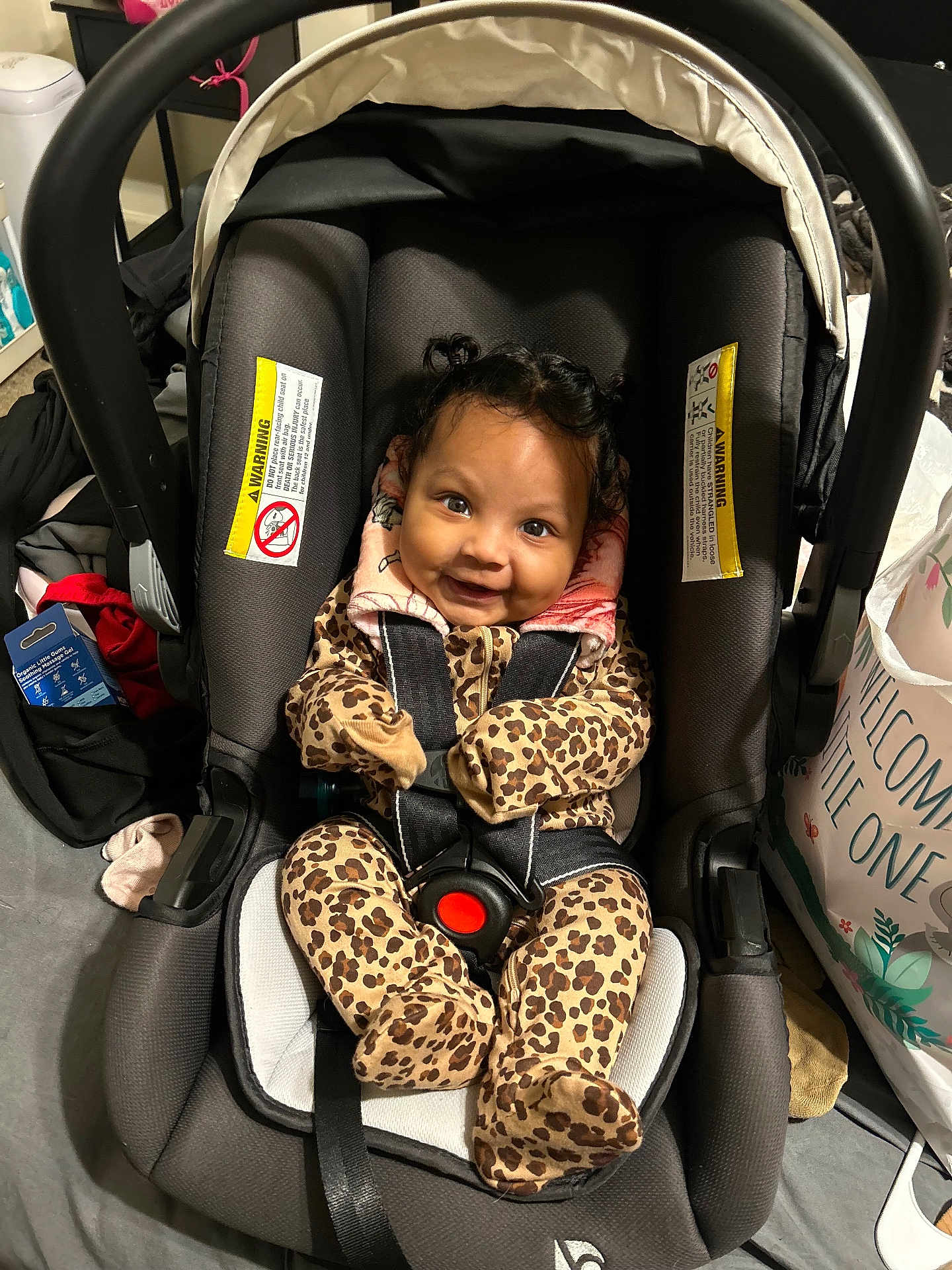 Mylianaa is registered to the contest to win money with this photo: baby, car_seat, leopard_print, onesie, smiling, infant, child, indoor, seatbelt, hair, face, happy, clothing, fabric, gift_bag, text_warning, black, gray, safety, person