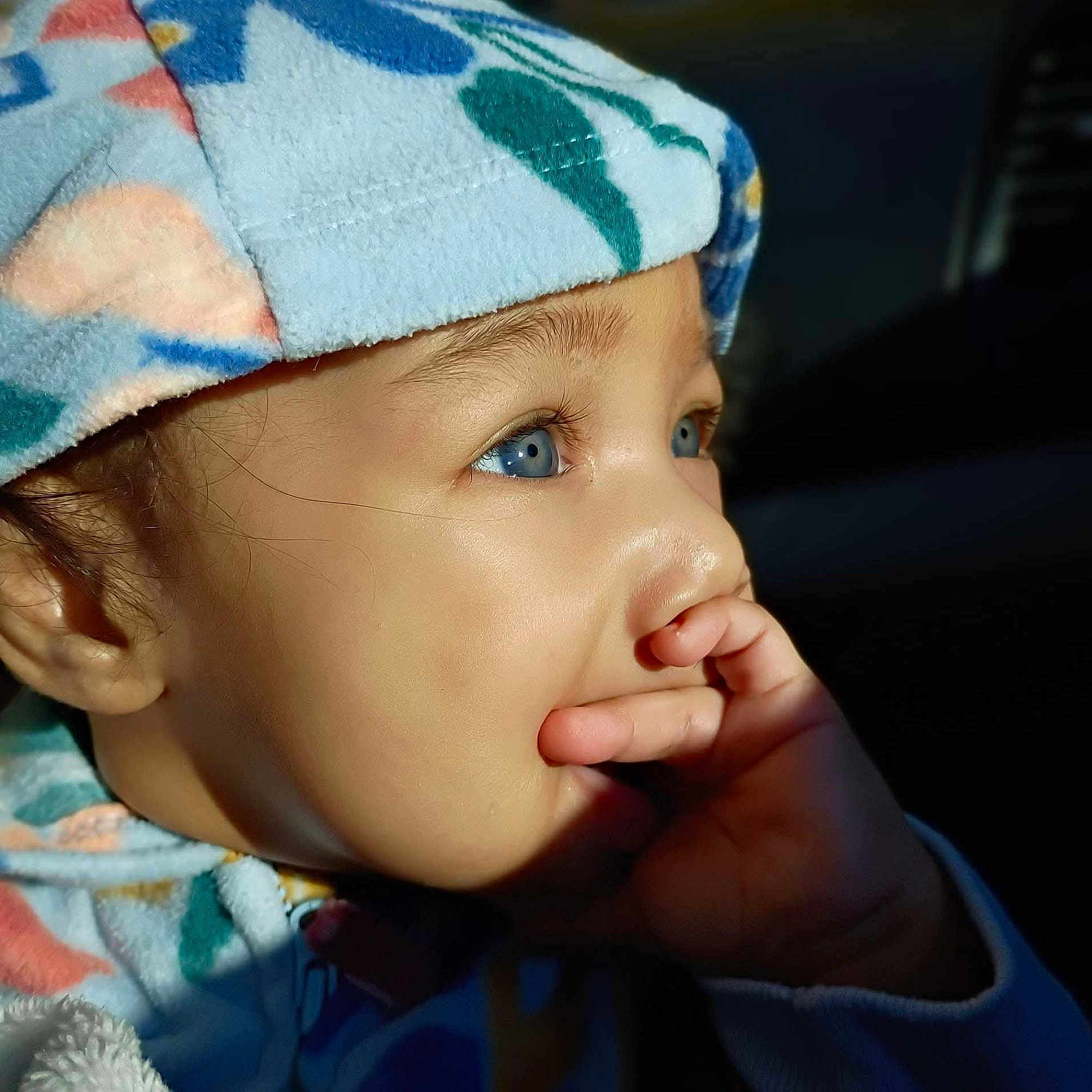 Ana is registered to the contest to win money with this photo: toddler, child, blue_eyes, hat, colorful_clothing, face, hand, fingers, profile, portrait, natural_light, curious, baby, warm_light, closeup, expression, skin, apparel, indoors, thoughtful