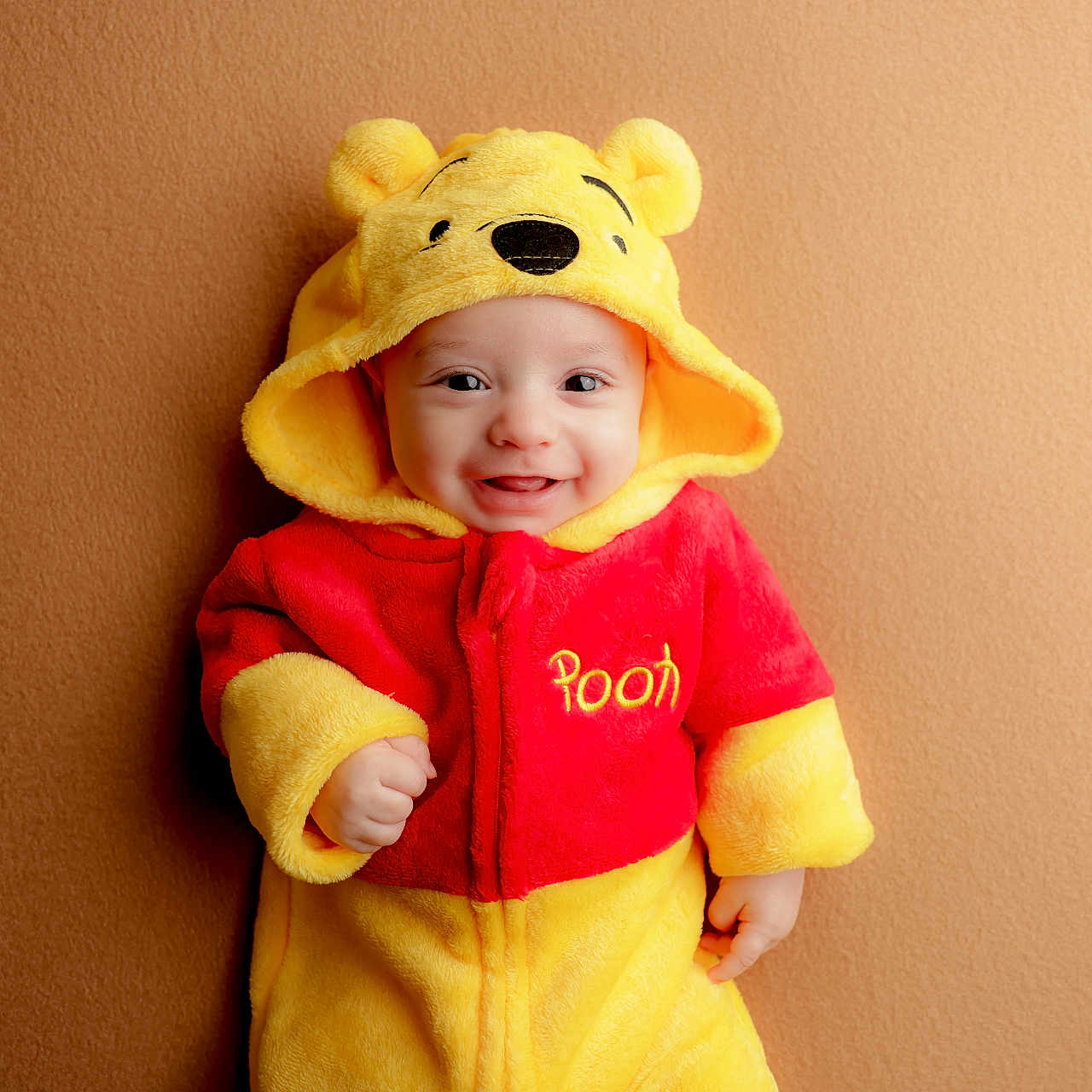 Liam joined the competition — help win amazing prizes! baby, baby_clothes, background, child, clothing, costume, cute, face, happy, hood, indoor, infant, onesie, person, portrait, red, smiling, warm_colors, winnie_the_pooh, yellow
