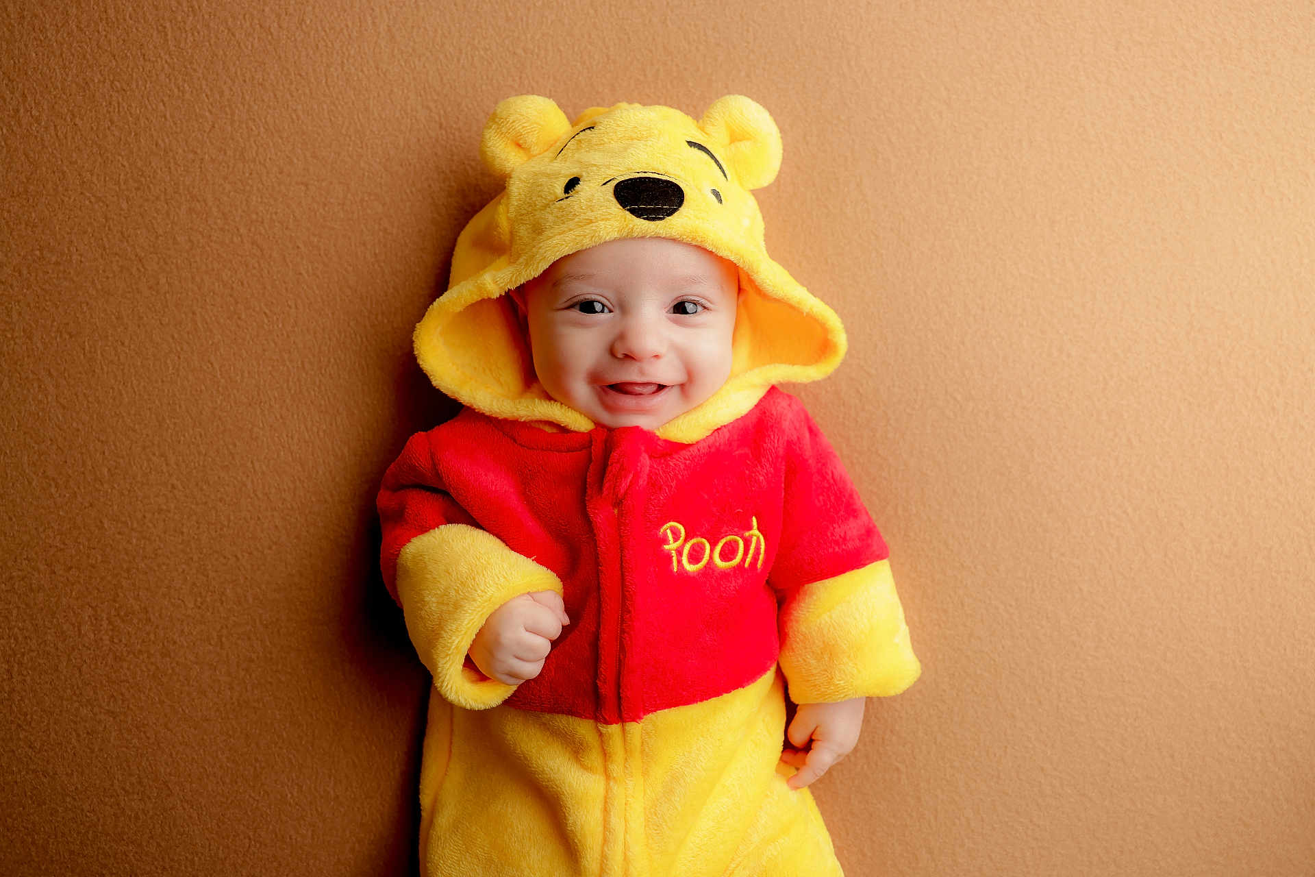Liam joined the competition — help win amazing prizes! baby, child, smiling, face, hood, costume, winnie_the_pooh, yellow, red, onesie, cute, happy, portrait, infant, clothing, indoor, warm_colors, person, baby_clothes, background