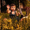 toddler, child, denim_overalls, grass, wildflowers, cowboy_boots, hat, sunlight, outdoor, nature, barn, rustic, greenery, feet, hand, expression, person, summer, daylight, playful