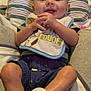 baby, child, smiling, bib, clothing, shorts, socks, shoes, hands, face, cushion, blanket, striped, indoor, happy, person, infant, seated, cute, young