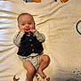 baby, infant, child, vest, bow_tie, striped_clothing, blanket, numbers, moon, smiling, lying_down, playful, cute, happy, indoors, soft_texture, portrait, young_child, baby_clothes, face
