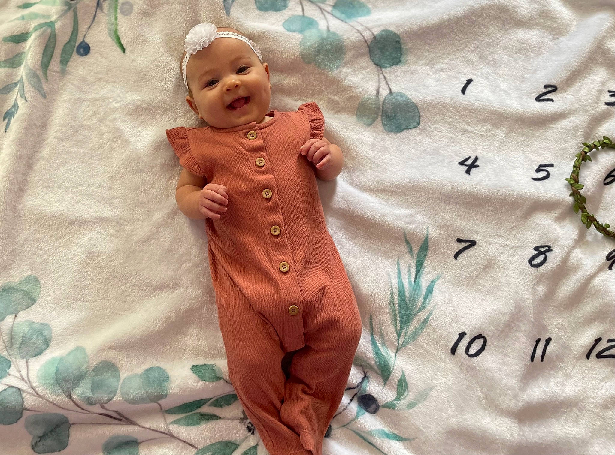 Ellora is registered to the contest to win money with this photo: arm, art, baby, baby_toddler_clothing, chest, doll, dress, fawn, gesture, hand, happy, linens, outerwear, pattern, person, sleeve, smile, textile, thumb, toddler