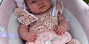 Evelyn is registered to the contest to win money with this photo: baby, infant, child, floral_clothing, hat, baby_seat, soft_toys, mobile, foot, hand, pink, white, cute, outdoor, green_grass, plush, comfort, portrait, relaxing, sun_hat