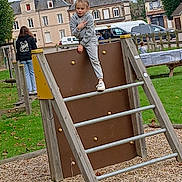 Kaly participe au concours pour gagner de l'argent avec cette photo : child, playground, climbing_structure, gray_tracksuit, peace_sign, park, grass, woodchips, trees, houses, cloudy_sky, casual_clothing, outdoor, daytime, person, play, fun, young, leisure, activity