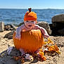 Jaxson is registered to the contest to win money with this photo: baby, pumpkin, orange_hat, beach, sand, ocean, rocks, autumn_leaves, fall, smiling, child, cute, outdoor, holiday, seasonal, portrait, nature, sunny, holiday_costume, playful