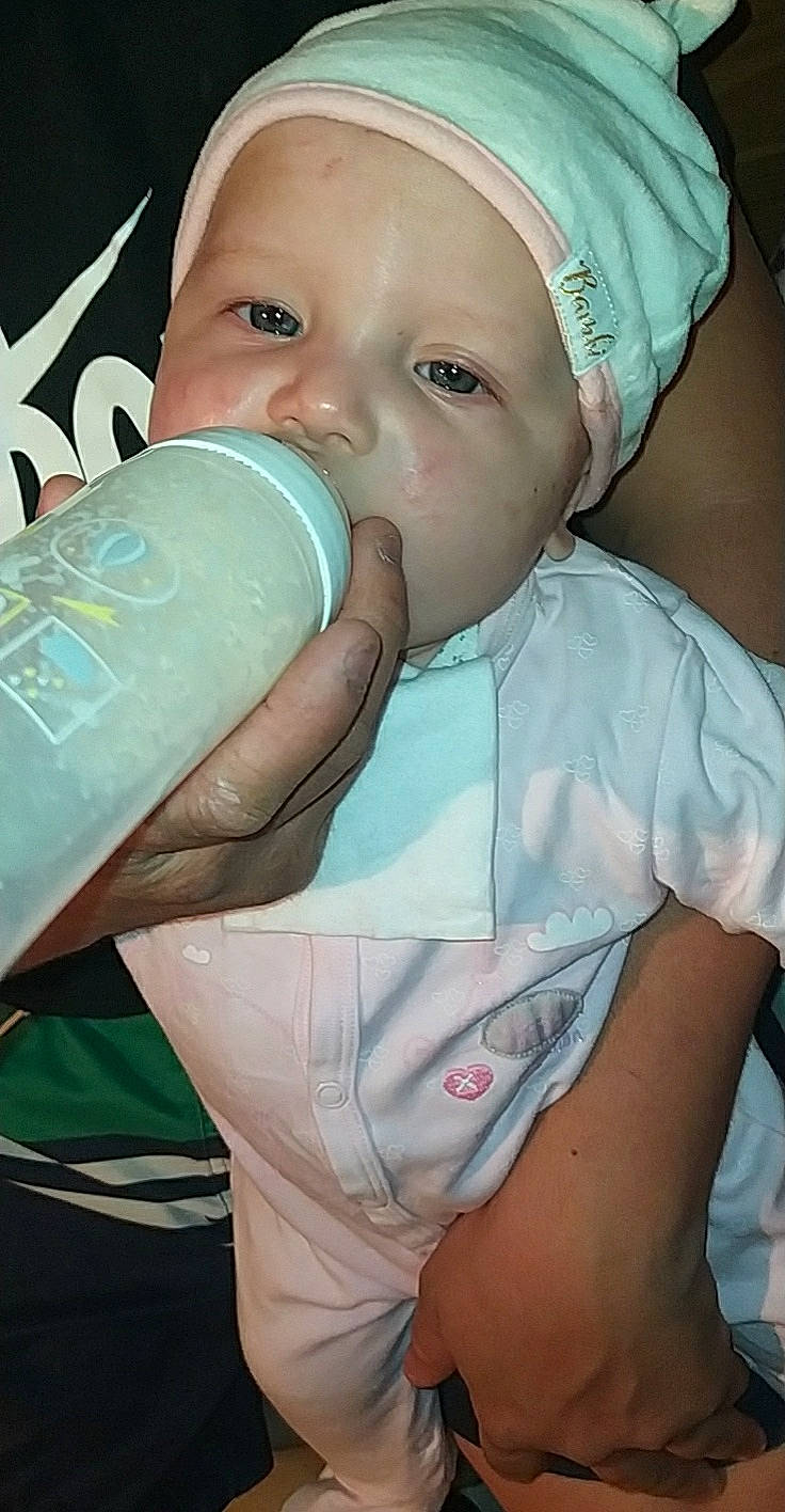 Moana participe au concours pour gagner de l'argent avec cette photo : baby, baby_bottle, baby_toddler_clothing, bottle, cheek, child, drinking, drinkware, ear, eye, eyelash, face, finger, headwear, nose, person, plastic_bottle, product, skin, sleeve