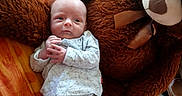 Maë participe au concours pour gagner de l'argent avec cette photo : baby, infant, teddy_bear, plush_toy, bed, blanket, clothing, sleepwear, comfort, cute, child, person, soft_toy, resting, indoors, cozy, small, lying_down, stuffed_animal, home