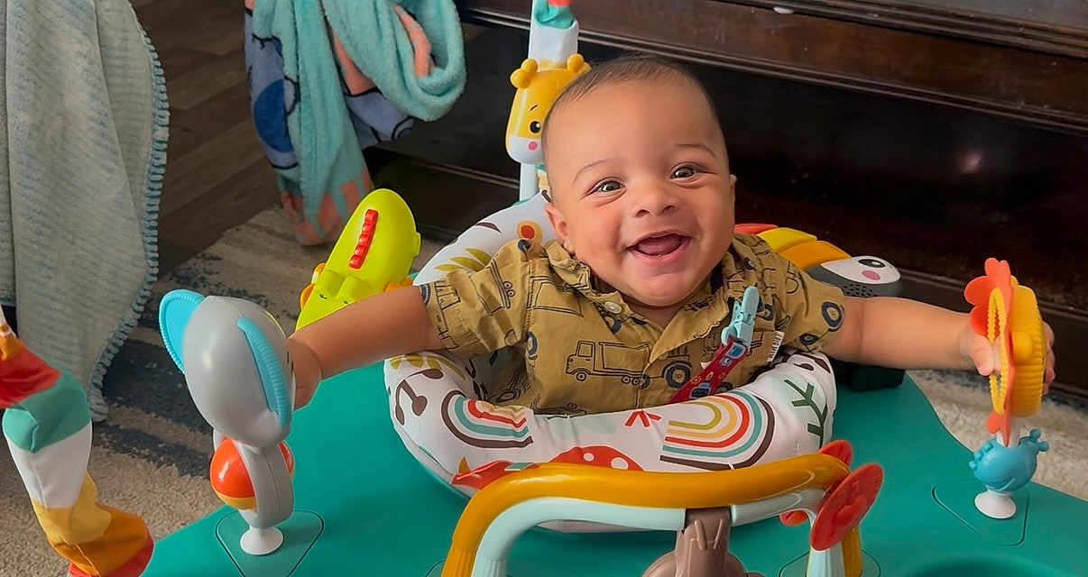 Jaidyn joined the competition — help win amazing prizes! activity_center, baby, blanket, child, clothing, colorful, cute, expression, face, furniture, happy, indoor, infant, joyful, person, play, sitting, smiling, toy, young_child
