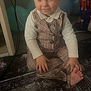 Jaxson joined the competition — help win amazing prizes! toddler, child, baby, plaid_clothing, vest, pants, sitting, smiling, indoor, balloons, party, carpet, floor, hand, foot, face, person, cute, decorations, background