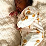 baby, sleeping, pajamas, blanket, infant, child, soft_texture, cozy, cute, peaceful, patterned_clothing, indoors, resting, warm, comfort, portrait, person, small_hands, curly_hair, sleep