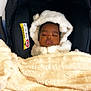 baby, sleeping, blanket, car_seat, soft_texture, hood, infant, child, peaceful, indoor, comfort, warm, black, cream, cozy, bundle, face, portrait, young, resting