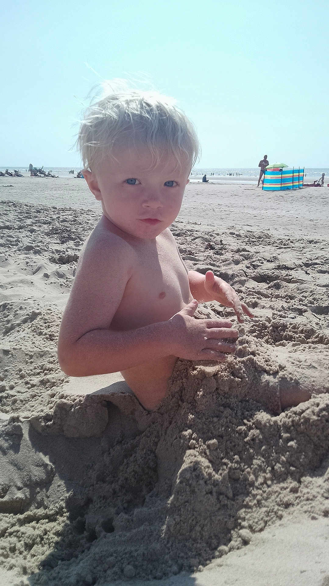 Raphaël a rejoint le concours — aidez-le/la à gagner de superbes lots ! child, beach, sand, playing, blonde_hair, blue_eyes, sunlight, summer, outdoor, person, vacation, holiday, nature, water, shore, seashore, sandcastle, fun, cute, portrait