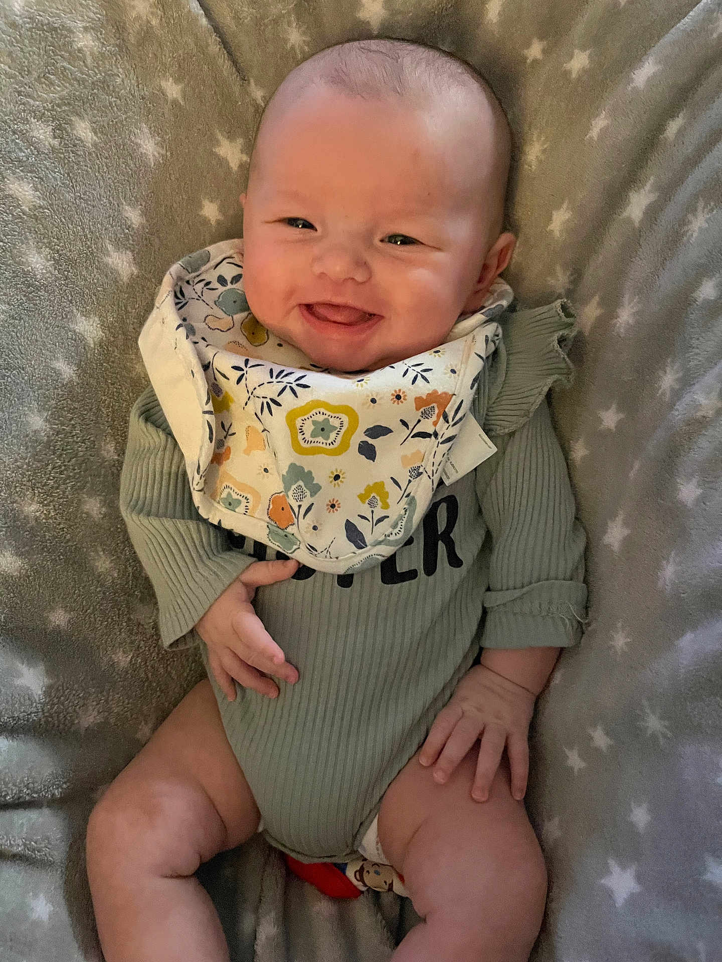 Raelon is registered to the contest to win money with this photo: baby, smiling, infant, onesie, bib, blanket, star_pattern, happy, cute, child, portrait, soft_texture, relaxed, indoors, skin, hand, face, legs, clothing, cozy