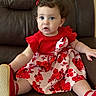 baby, child, curly_hair, cute, dress, fashion, floral_pattern, furniture, girl, hair_bow, indoors, leather_chair, photography, portrait, red_clothing, shoes, sitting, smiling, toddler, wide_eyes