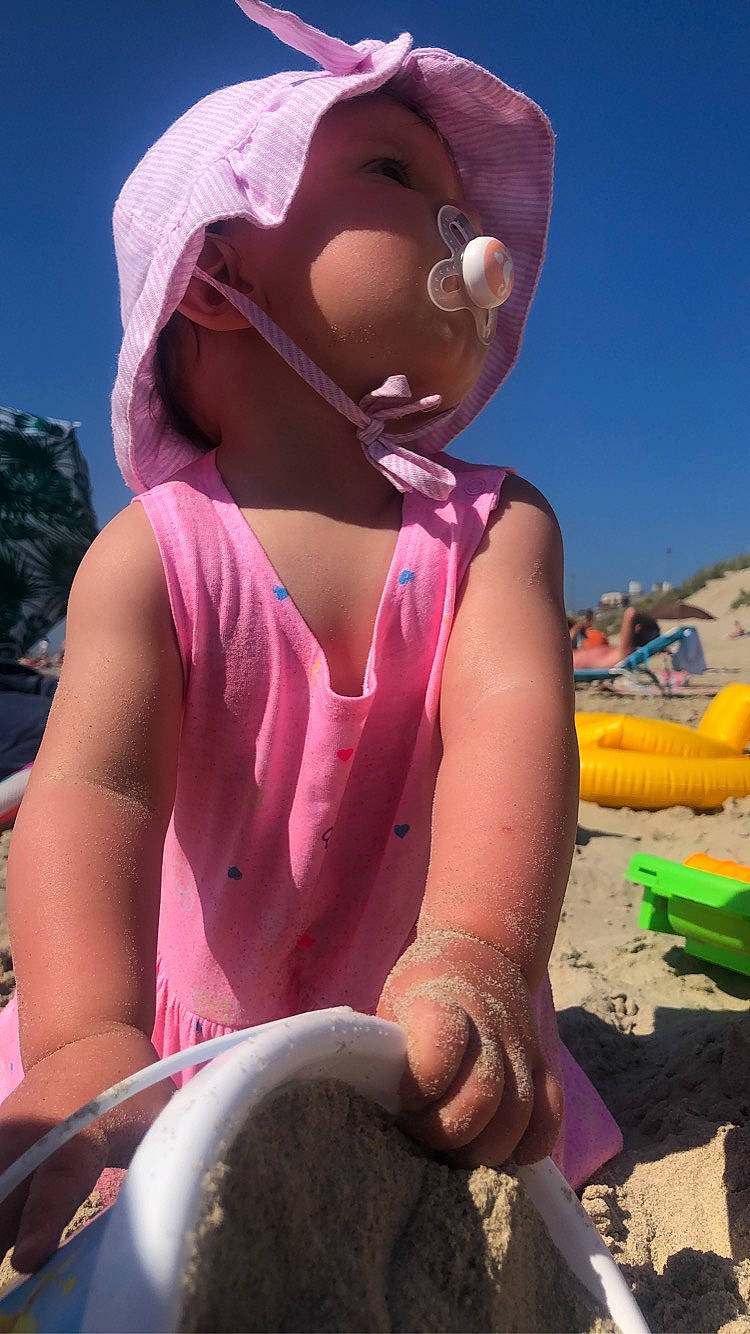 Djenna participe au concours pour gagner de l'argent avec cette photo : boats_and_boating_equipment_and_supplies, cap, eyewear, fun, happy, hat, landscape, leisure, magenta, mammal, people_in_nature, personal_protective_equipment, pink, recreation, sand, sky, summer, sun_hat, toddler, travel