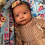 baby, infant, headband, flower, dress, blanket, pattern, face, person, child, cute, indoors, soft, colorful, textile, portrait, closeup, lying_down, expression, warm