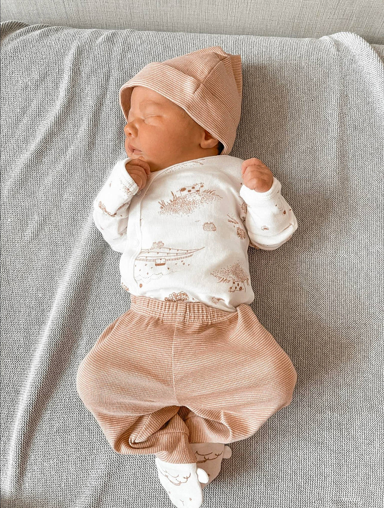 Sterling is registered to the contest to win money with this photo: baby, baby_products, baby_sleeping, baby_toddler_clothing, beige, cap, child, collar, comfort, hat, headgear, linens, pattern, peach, person, sitting, sleeve, textile, toddler, wood