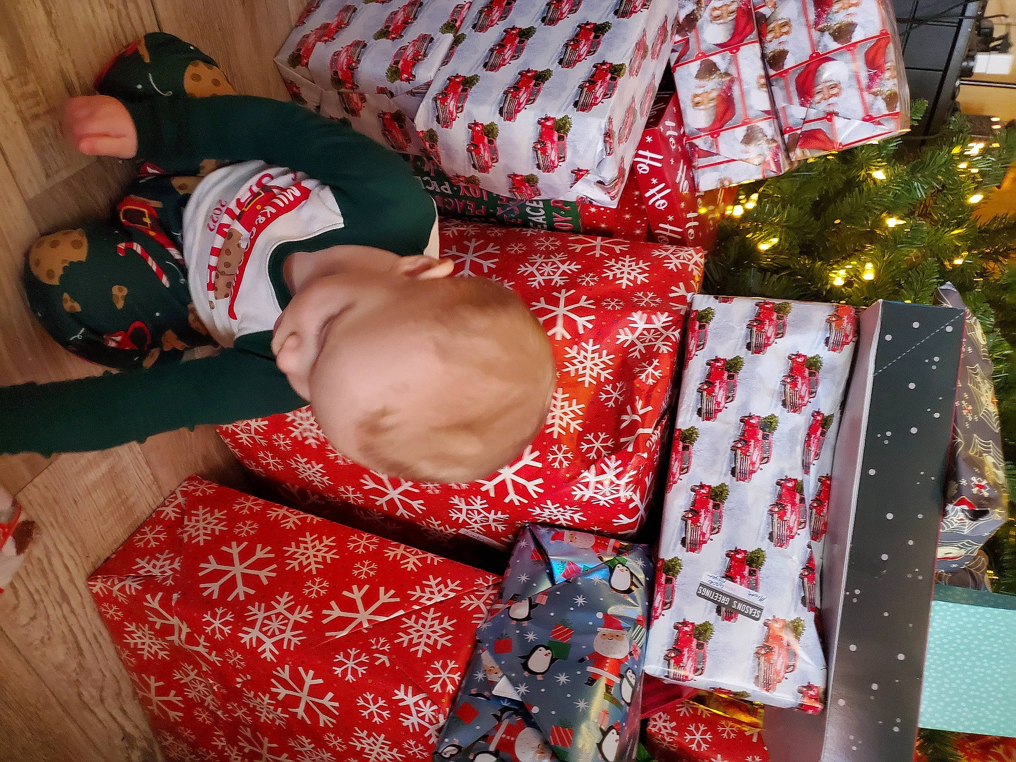 Micah joined the competition — help win amazing prizes! baby, baby_toddler_clothing, carmine, child, christmas, christmas_decoration, christmas_eve, decoration, event, gift_wrapping, happy, holiday, lap, linens, pattern, person, room, smile, textile, thigh