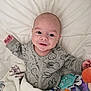 baby, infant, smile, blanket, toys, onesie, bunny_prints, lying_down, cozy, happy, child, cute, indoors, soft_texture, playful, colorful, portrait, young_child, expression, comfort